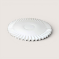 A round white milk glass cake salver with a clear ruffled edge on a light beige backdrop