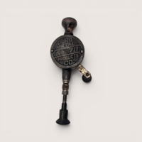 Antique metal hand crank valve lapping tool with a turned wood knob and suction cup base on a solid background.