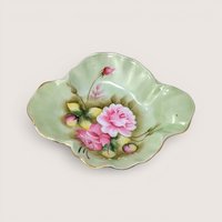 Fluted pale green porcelain candy dish with hand painted pink roses and gold gilt edges on a solid background.