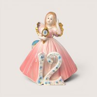 Porcelain birthday angel figurine in a pink gown holding a hand mirror behind a floral number 12 on a solid background.