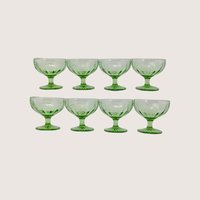Eight green depression glass sherbet cups arranged in two rows of four against a plain off-white background
