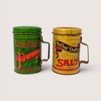 A set of green and yellow vintage tin salt and pepper shakers with handles on a plain white background