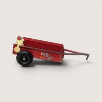 A vintage red die cast metal farm implement toy spreader with black tires and honest play wear.