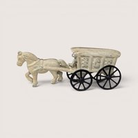An antique white cast iron toy horse pulling an ice wagon with large black spoked wheels against a plain background.