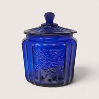 A rich cobalt blue lidded cookie jar with an embossed open rose pattern on the paneled sides.