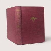 1950 vintage red cloth hardcover copy of The Wisdom of the Sands by Antoine de Saint-Exupéry standing upright against a plain linen background.