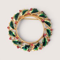 Vintage gold-tone enamel holly wreath brooch with green leaves and red berry details.