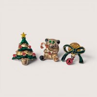 Set of three vintage gold-tone enamel Christmas pins featuring a tree, a candy cane bear, and a jingle bell bow.
