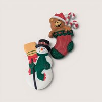 Pair of vintage Hallmark holiday brooches featuring a snowman with a broom and a teddy bear in a Christmas stocking.