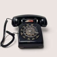 1984 AT&T vintage black rotary desk phone with a circular dial and coiled cord.