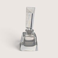 A vintage clear glass perfume bottle featuring a square base and a tall geometric frosted glass stopper against a neutral background.