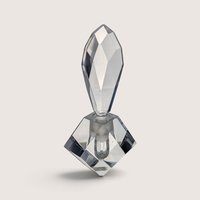 A vintage heavy cut crystal perfume bottle featuring a diamond-shaped base with a red foil label and a large multi-faceted teardrop stopper against a neutral background.