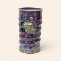 Handmade colorful stoneware vase featuring a ribbed body and purple, blue, and gold drip glaze.