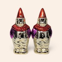 Pair of vintage metallic clown salt and pepper shakers with red hats and purple sleeves.