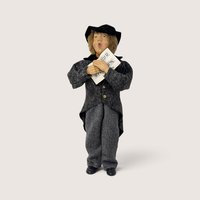 Vintage molded plastic Christmas caroler figurine wearing a grey coat and holding sheet music.