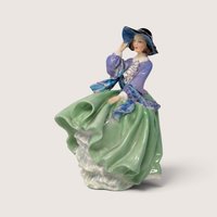 Vintage Royal Doulton porcelain Top O the Hill figurine depicting a lady in a green skirt and blue bodice adjusting her hat.