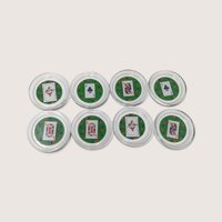 A set of 8 round glass coasters featuring miniature playing card inserts including jokers, kings, queens, and aces against a green background.