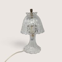 A small vintage clear cut glass boudoir lamp featuring a patterned shade with frosted floral details and a fluted base against a neutral background.
