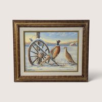 An original framed painting by Martha Spear depicting a rooster and hen pheasant standing in a snowy field beside an old wooden wagon wheel, set inside a textured wood frame with a fabric liner, showing the Fredrix canvas backing on the rear.