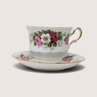 A vintage Queen Anne bone china tea cup and saucer set adorned with pink and white roses and gold trim, paired with its backstamp showing the maker's mark.