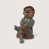 A vintage Tom Clark signed "Marty" resin gnome figurine from Cairn Studio, sitting with crossed legs and a laughing expression.