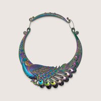An iridescent rainbow-sheen metal statement bib necklace featuring an ornate engraved peacock motif and a structured collar shape.