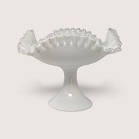 A large vintage white milk glass pedestal bowl with a dramatic swung ruffled rim and a solid footed base.