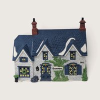 A vintage Department 56 Dickens Village Brownlow House building featuring a blue shingle roof with snow accents, white brick walls, and an ivy vine across the front.