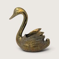 A vintage solid brass swan planter with a curved neck, polished golden body, and detailed feather texture on the wings.