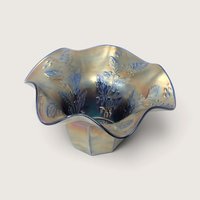 A vintage Fenton blue carnival glass fluted vase featuring an embossed holly pattern and a ruffled edge on a neutral background.