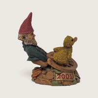 A close-up view of a Tom Clark and Tim Wolfe signed gnome figurine showing dual artist signatures on the textured leaf base.