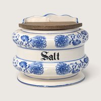 A vintage blue and white ceramic wall-hanging salt bin with a weathered wooden lid and Blue Onion patterns against a neutral background.