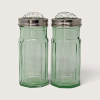 A pair of vintage green glass panel-cut vases featuring metal screw-on caps with domed wire flower frog inserts against a neutral background.