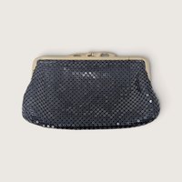 Vintage Whiting and Davis International black metal mesh evening clutch purse with gold-tone kiss lock on a light background.   