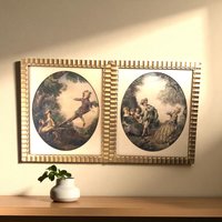 A pair of vintage framed prints depicting 18th-century French Rococo scenes with figures in elegant attire playing on a seesaw and in a park, set in matching fluted gold frames.