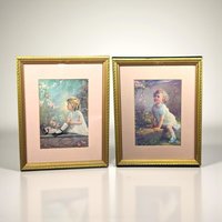 Two matching vintage wood frames containing portrait prints of little girls. One print, "Song of the Bluebird" by Zula Kenyon, shows a girl in a soft dress looking upward at a bird. The second, "Song of the Lark" by Florence Lindsey, features a similar ethereal portrait. The frames have a dark, aged finish with ornate period detailing.