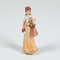 A matte porcelain figurine of a woman in Edwardian-era winter attire. She wears a tan long-sleeved coat with fur cuffs, a matching fur hat with a pink feather, and a large white bow. She holds a patterned muff and a small card.