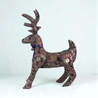 A standing plush reindeer made from fabric with an intricate purple and earth-toned paisley pattern. It features large antlers, button-jointed legs, and a purple ribbon with a small gold bell around its neck.