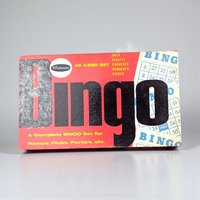 A rectangular vintage game box with a vibrant red background. Large black and gray "BINGO" text dominates the center, flanked by illustrations of blue and white bingo cards. The surface shows a slight linen-like texture and minor edge wear.