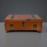 A rectangular wooden box with a smooth, polished finish. The wood grain is prominent, showing a warm honey-oak tone. It features a hinged lid and simple, clean lines without ornate carvings or metal hardware on the exterior.