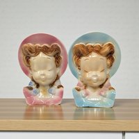 A pair of ceramic wall pocket planters shaped like elegant female heads. They feature classic mid-century hand-painted details with soft, airbrushed color transitions. The silhouettes are designed with a flat back and a pre-drilled hole for secure wall hanging.