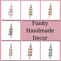 Set of seven handmade wall hangings made of interlocking clear plastic cups and colorful faceted beads. Features vibrant red, blue, and gold patterns. Each piece is suspended from a gold-toned rod with white end caps.