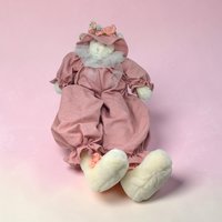 A large cream-colored handmade plush cat with exceptionally long, slender limbs and a hand-stitched face. The cat is shown in a seated position with a weighted base and wears a vintage-style fabric outfit with a lace collar.