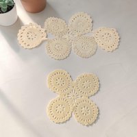 Two ivory hand-crocheted doilies in contrasting shapes. One large elongated oval with an openwork floral center and one smaller square doily with a dense geometric pattern. Both feature a warm, aged patina.