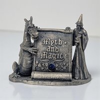 A detailed pewter figurine featuring a robed wizard and a dragon standing on opposite sides of a rustic stone signpost. The base is textured like a rocky path, and the entire piece has a dark, antiqued pewter finish.