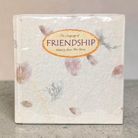 A square hardcover book with a textured, cream-colored handmade paper cover. Pressed pink leaves and grey botanical sprigs are embedded into the paper. An oval orange label on the front features the title in purple script.