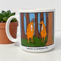 A white ceramic coffee mug featuring a cartoon of two deer, one with a target-shaped birthmark. The texture is smooth glazed ceramic with a cylindrical silhouette and a standard C-shaped handle.