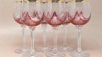 A set of six wine glasses with cranberry red bowls featuring frosted etched floral patterns and gold rims. The stems are tall, clear, and multi-faceted with a flat circular base.