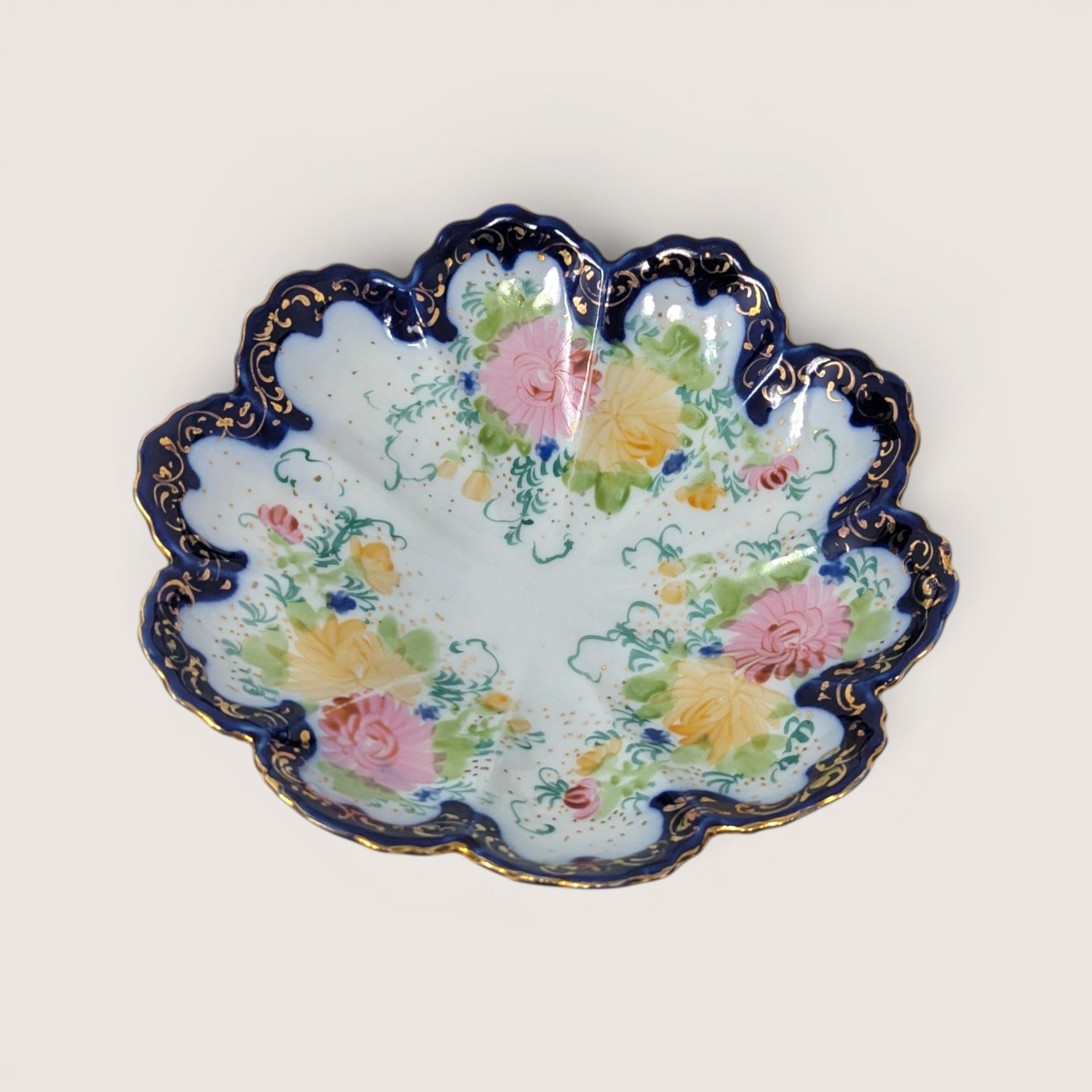 Vintage hand-painted porcelain bowl featuring a scalloped cobalt blue and gold gilt rim with delicate floral details.