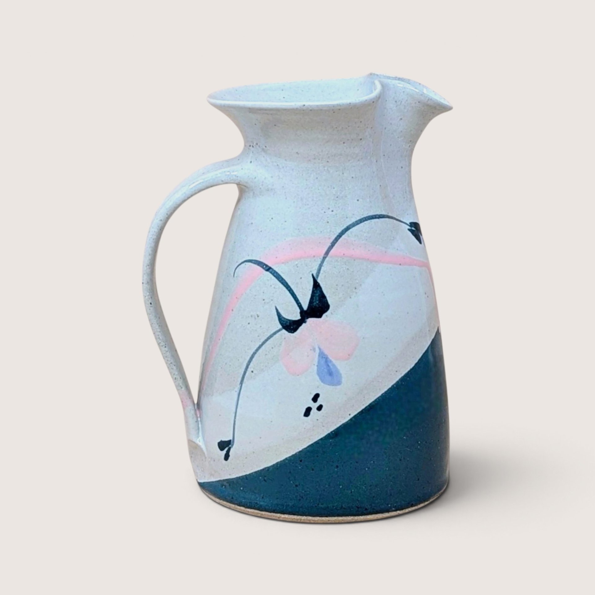 Vintage speckled earthenware pitcher featuring a teal color block base and pastel hand-painted floral design.